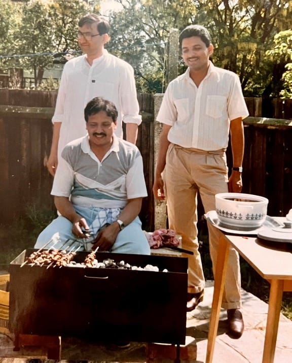 Three men outside beside a barbecue