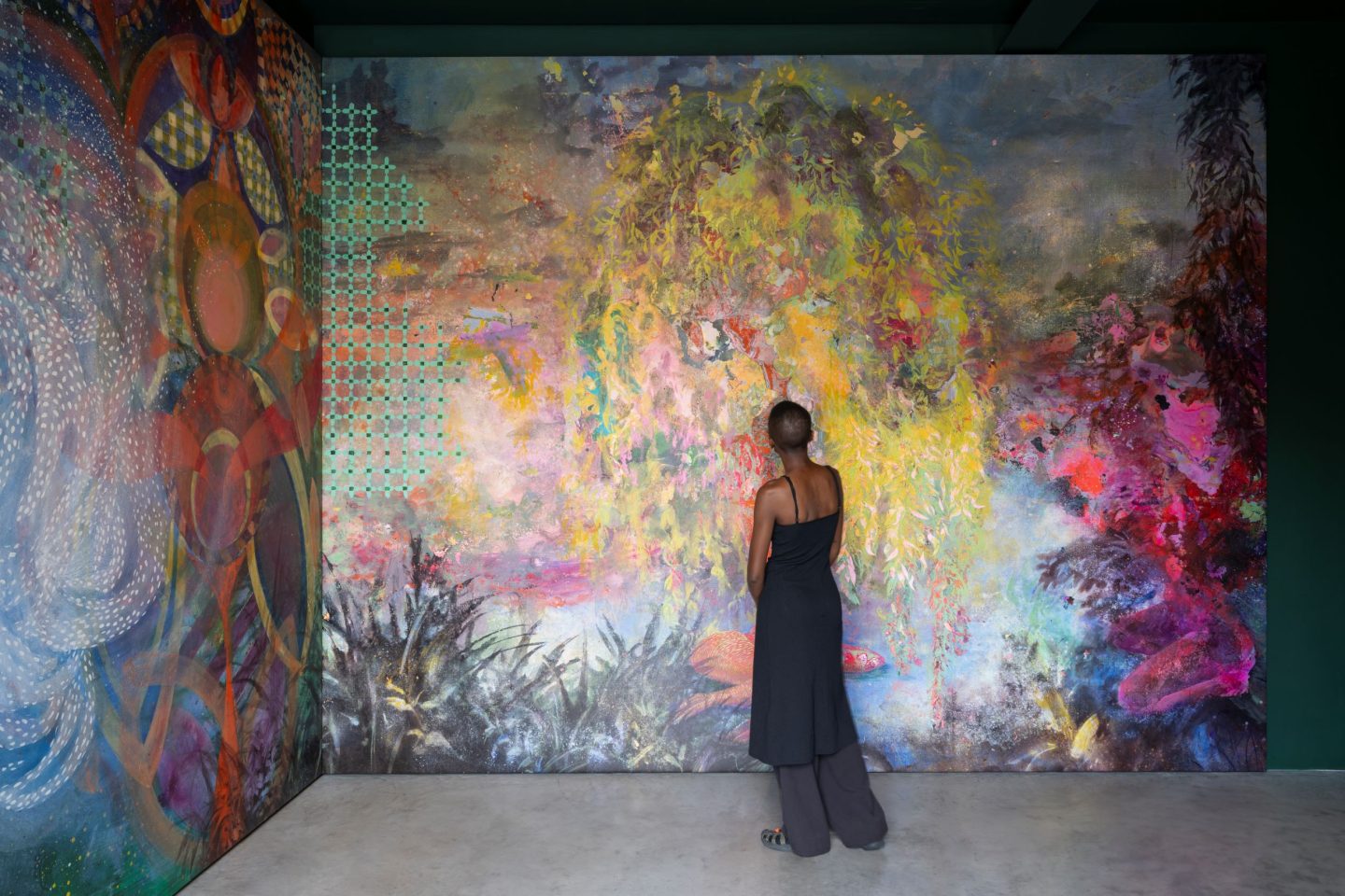 A blurred shot of a colour mural resembling a jungle-like location. A person stares at the details of the colours.